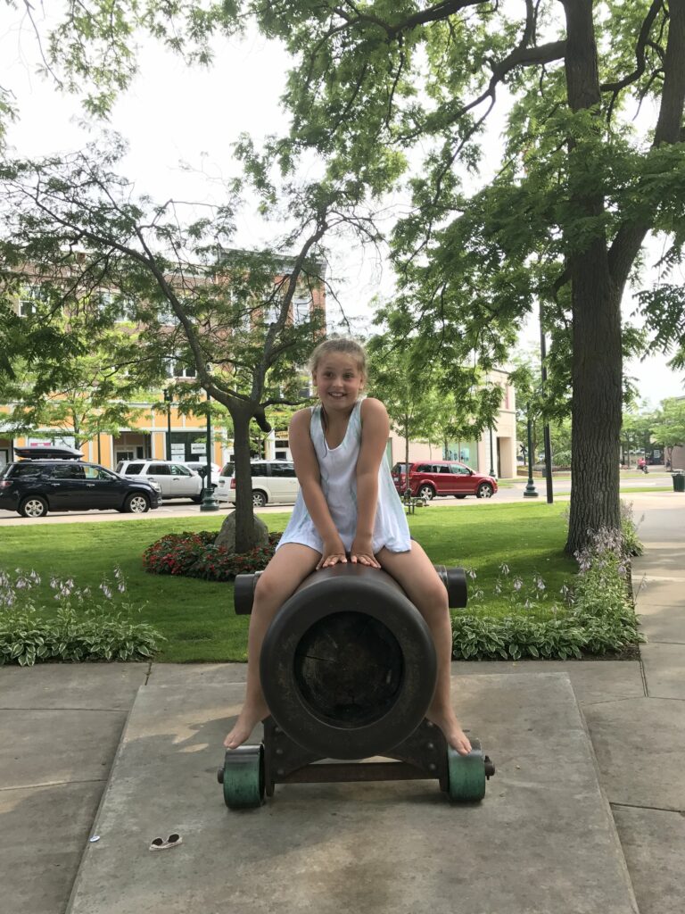 A child sits on top of the cannon.
